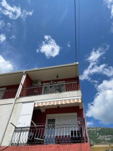 a red building with a balcony and a blue sky at Apartments Neda in Sutomore