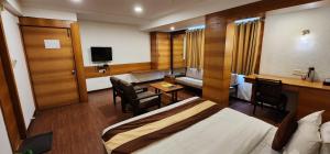 a hotel room with a bed and a desk and a tv at Hotel Kanak in Ahmedabad