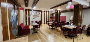 a dining room with tables and chairs in a restaurant at Hotel Kanak in Ahmedabad