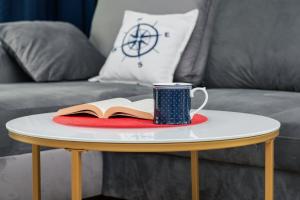 stolik kawowy z książką i kubkiem w obiekcie Apartment Redlowo & 2 bedrooms & Parking by Renters w mieście Gdynia