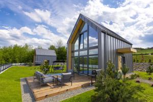 a small house with a deck and glass windows at Sośnie Górne Resort & Spa in Grybów