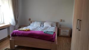 a bedroom with a bed with a purple blanket at Apartamenty Łąkowa Piecki in Piecki