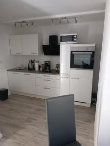 a kitchen with white appliances and a chair in a room at Ferienwohnung Herzberg in Loxstedt
