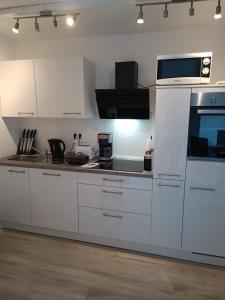 a kitchen with white cabinets and a microwave at Ferienwohnung Herzberg in Loxstedt