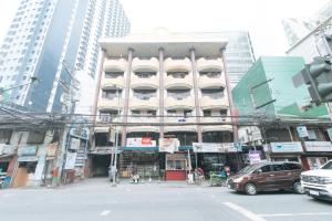 a tall building with cars parked in front of it at Mervin's Terraces by RedDoorz in Manila
