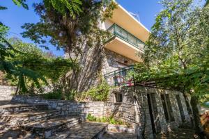 a stone house with a tree in front of it at Petra Mare Apartments in Alyki