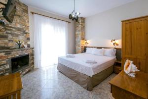 a bedroom with a large bed and a fireplace at Petra Mare Apartments in Alyki