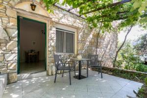 a patio with chairs and a table in a stone building at Petra Mare Apartments in Alyki