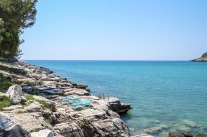 a group of blue lounge chairs on a rocky shore at Petra Mare Apartments in Alyki