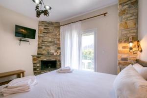 a bedroom with a white bed and a fireplace at Petra Mare Apartments in Alyki