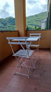 2 chaises assises sur un balcon avec une table dans l'établissement Casa Daniela, à Bagni di Lucca