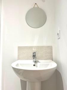 ein weißes Waschbecken mit einem runden Spiegel darüber in der Unterkunft *Marquer* Studio proche gare M23 in Annemasse
