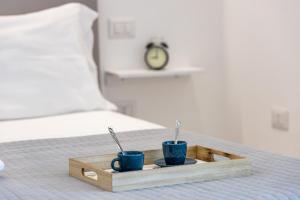 dos tazas azules en una bandeja de madera en una cama en Baia del Sole, en Olbia