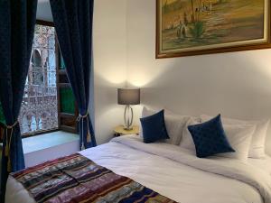Schlafzimmer mit einem Bett mit blauen Vorhängen und einem Fenster in der Unterkunft Riad Malida Marrakech in Marrakesch