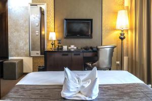 ハイドゥソボスローにあるHotel Délibábのベッドとテレビが備わるホテルルームです。