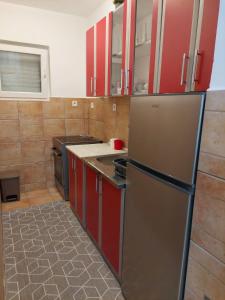 cocina con armarios rojos y nevera de acero inoxidable en Jana apartments, en Tivat