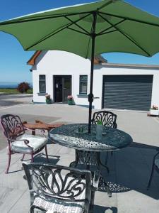 a table and chairs with a green umbrella at Luxury holiday rental with sea views on the Wild Atlantic Way in Tralee