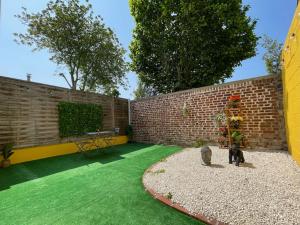 a backyard with a brick wall and green grass at Peaceful Apparts Saint-Quentin in Saint-Quentin
