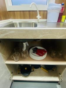 a kitchen sink with plates and utensils on a shelf at LOFT PRÓXIMO AO FORUM in Chapecó