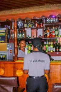 un homme debout devant un bar dans l'établissement SILVER HOTEL APARTMENT Near Kigali Convention Center 10 minutes, à Kigali