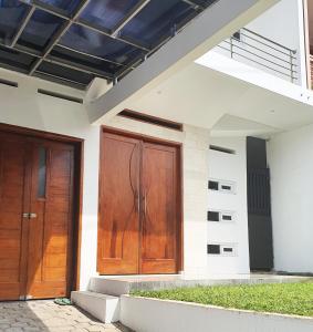 une paire de portes en bois sur le côté d'une maison dans l'établissement Cozy Villa / Rumah Sejuk City View Bandung, à Bandung