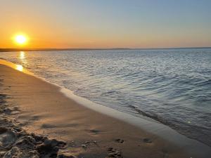 a beach with the sun setting over the water at Prawdzic Family Resort & Wellness in Gdańsk
