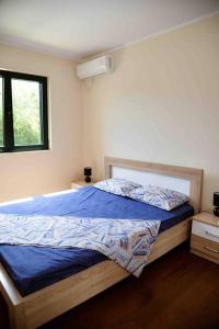 Schlafzimmer mit einem Bett mit blauer Bettwäsche und einem Fenster in der Unterkunft The Wave in Tivat