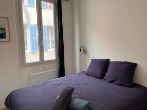 sypialnia z łóżkiem z fioletową pościelą i oknem w obiekcie Le panier de Clarisse w Marsylii
