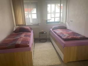 twee bedden in een kamer met twee ramen bij Gemütliche Ferien in Lauchheim