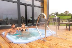 a man and a woman sitting in a hot tub at Sośnie Górne Resort & Spa in Grybów