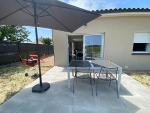 a table and chairs with an umbrella on a patio at Maison cosy à Fronton in Fronton
