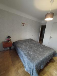 1 dormitorio con cama con colcha gris y mesa en La Maison de Raph, en Villeneuve dʼOlmes