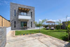 a stone house with a yard with a patio at Hermagio Villa Hermione by Estia in Malia
