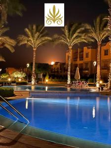 a large swimming pool with palm trees at night at Luxury Chalet in Mountain View 2 , El-Sokhna with Sea View , Pool View "Heated Pool" and Garden View Families Only in Ain Sokhna