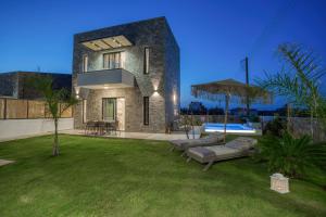a house with a lawn and a swimming pool at Hermagio Villa Hermione by Estia in Malia