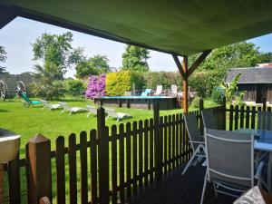 una valla con sillas y una mesa en un patio en La petite maison dans la prairie, en Notre-Dame-du-Touchet