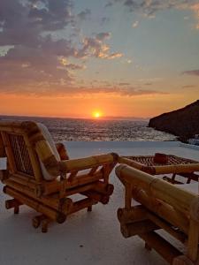 two chairs on the beach with the sunset in the background at Sunset Apartment in Patmos