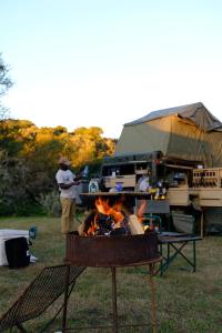 a man standing next to a fire in front of a tent at Dream Cruiser in Addo with Private Bath in Kirkwood