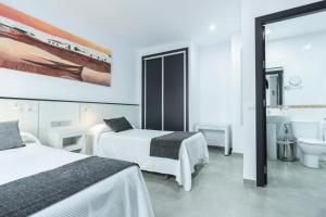 a hotel room with two beds and a bathroom at Hostal El Yunque in Conil de la Frontera
