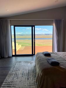 a bedroom with a large glass door with a view of the ocean at Luxury villa with hot tub & amazing view in Reykholt