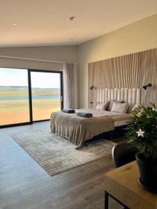 a bedroom with a large bed and a large window at Luxury villa with hot tub & amazing view in Reykholt