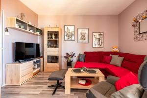 Apartment Lotus في تروغير: غرفة معيشة مع أريكة حمراء وتلفزيون