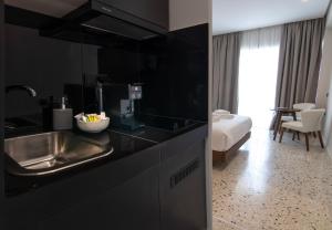 una cocina con fregadero y una cama en una habitación en Mythodea Athens Suites en Atenas