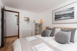 a white bedroom with a large white bed with pillows at Porthcurno Barns, The Big Barn - Spacious & cosy cottage, walk to Porthcurno beach, Pedn Vouder & Minack Theatre in Penzance