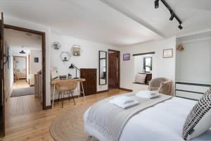 a white bedroom with a bed and a desk at Porthcurno Barns, The Big Barn - Spacious & cosy cottage, walk to Porthcurno beach, Pedn Vouder & Minack Theatre in Penzance