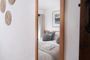 a mirror in a bedroom with a bed at Porthcurno Barns, The Big Barn - Spacious & cosy cottage, walk to Porthcurno beach, Pedn Vouder & Minack Theatre in Penzance