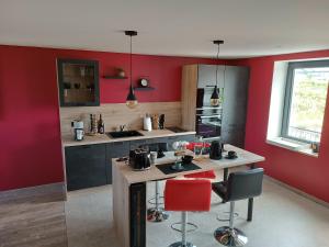 a kitchen with red walls and a counter with red chairs at La bulle beaujolaise in Juliénas