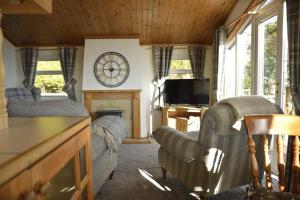 a living room with couches and a fireplace with a clock at Lochhill Stable Lodge in Castle Douglas