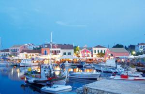 Un grupo de barcos atracados en un puerto con edificios. en Stella Cottage, en Fiskardho