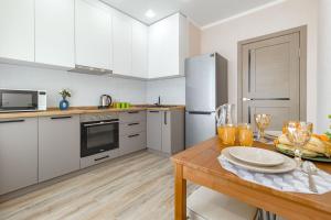 een keuken met witte kasten en een houten tafel bij Апартаменты в ЖК Only Sun - 3 in Astana